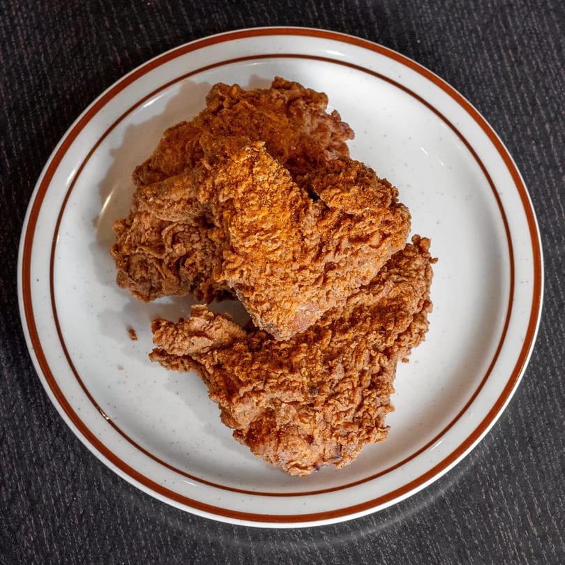Crispy, golden-brown fried chicken pieces on a white plate with a brown rim at Mirchi Cafe.