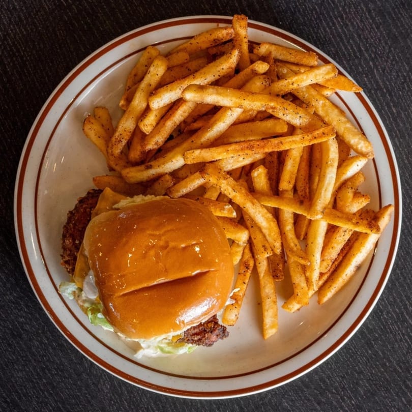 A Mirchi Cafe halal burger with lettuce, cheese, and a side of seasoned french fries.