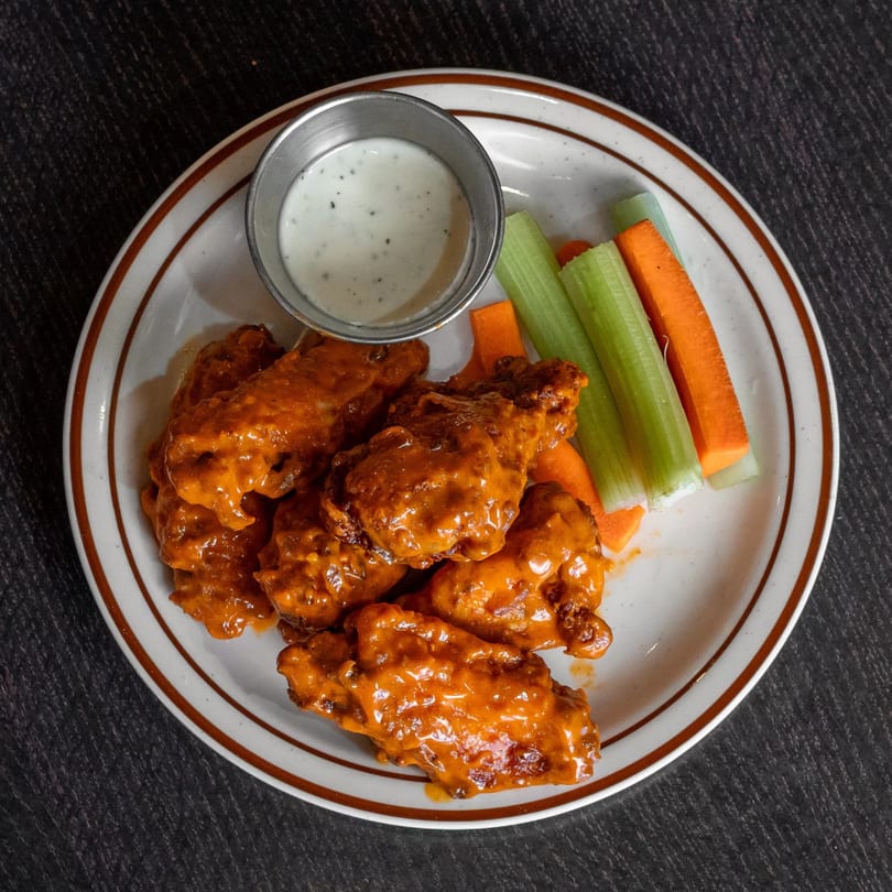 A plate of Mirchi Cafe's halal buffalo wings with ranch, celery, and carrot sticks.